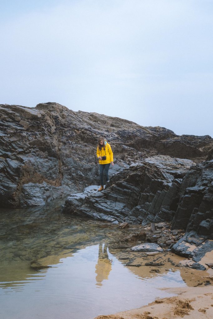 kelly with her yellow jacket standing on the rocks near a tidal pool