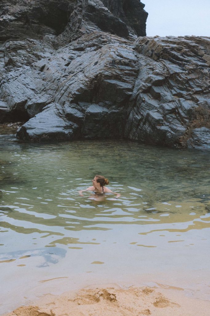 kelly swimming in a tidal pool on a grey day in cornwall