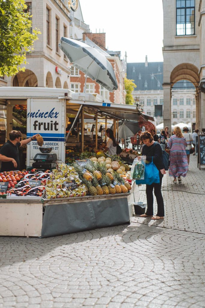 woman buying fruit at a market stall in leuven