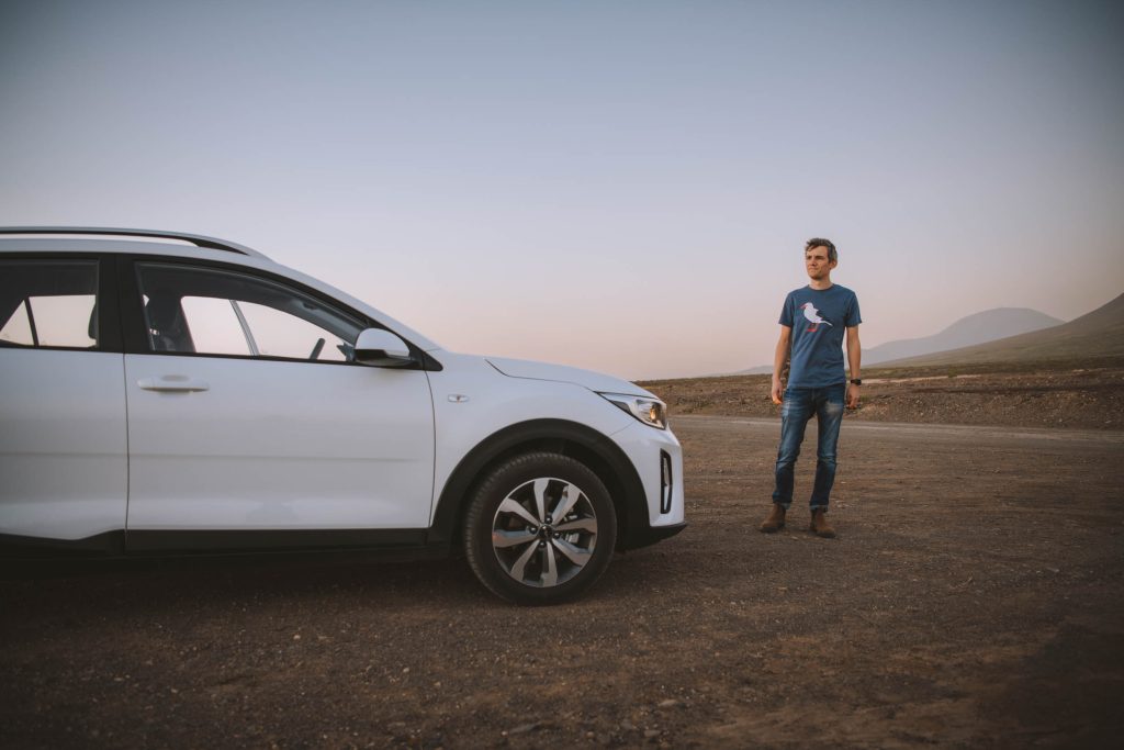 Florian posing with white rental car during sunset