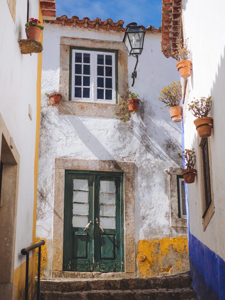 narrow street with white house with a green wooden door and cute window