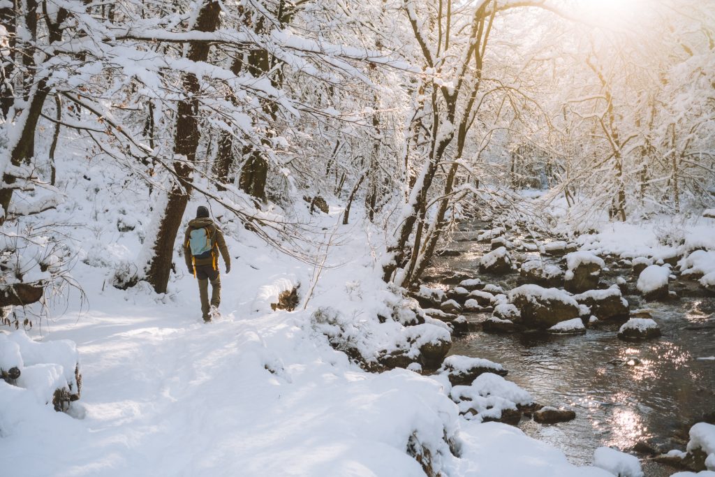 florian walking in the snow next to a river in the ardennes