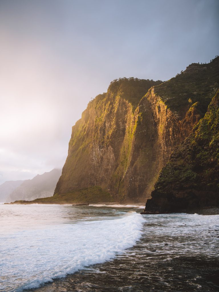 sun hitting the cliffs by the ocean at guindaste in madeira