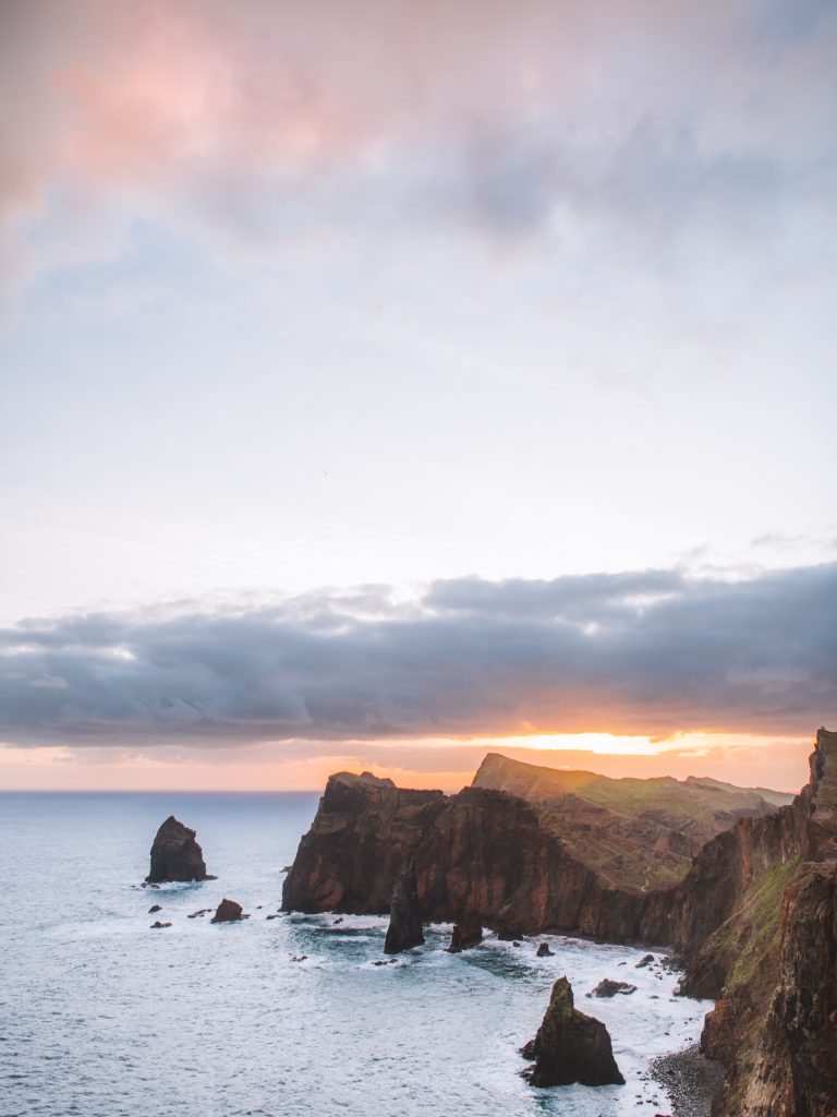 view of cliffs in the ocean with sun rising behind in madeira