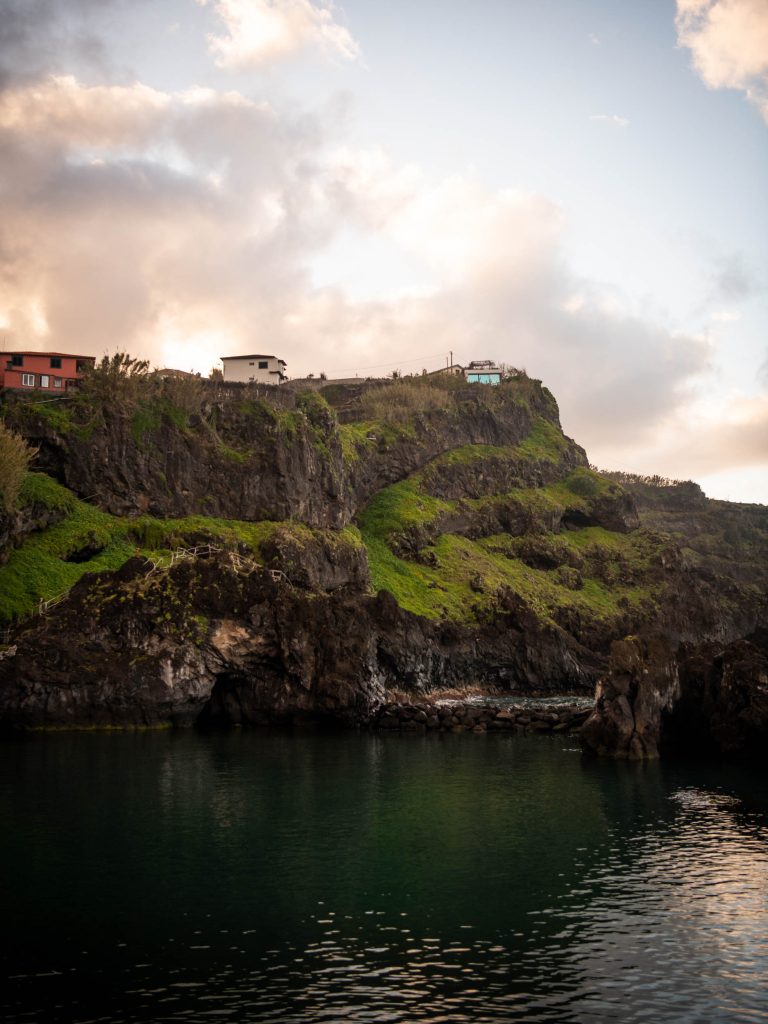 three houses on top of a cliff next to the ocean