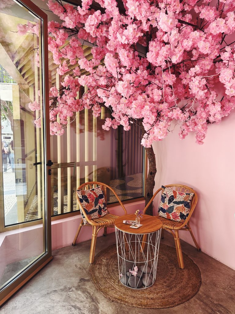 pink blossoms above a cute table with chairs to sit in Mya Petit Cafe in Funchal Madeira