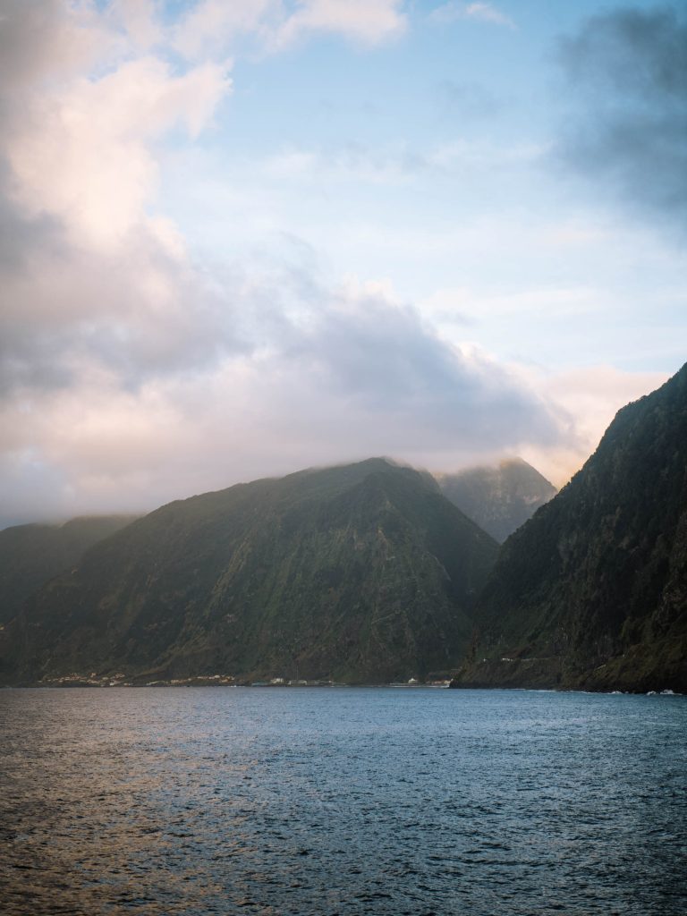 view of the ocean with big mountains in the clouds during sunset