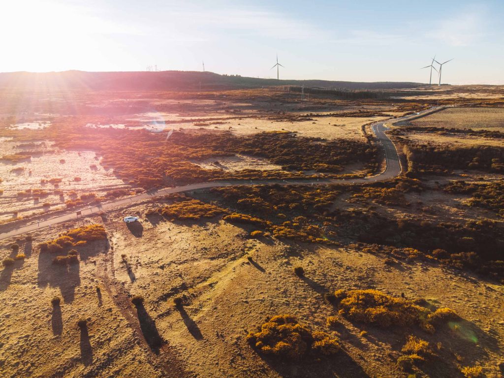 drone shot of the road and windmills in the back at paul da serra plateau in madeira