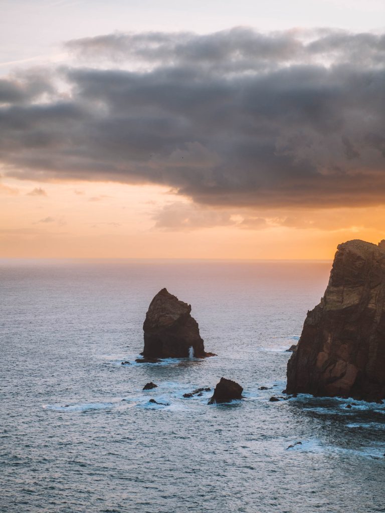 cliff and rocks in the ocean during sunrise at ponta do rosto