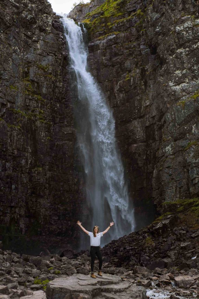 kelly standing in front of the Njupeskär waterfall in sweden