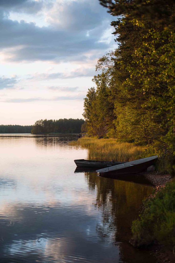 two boats lying partly in the water and on the shore during sunset