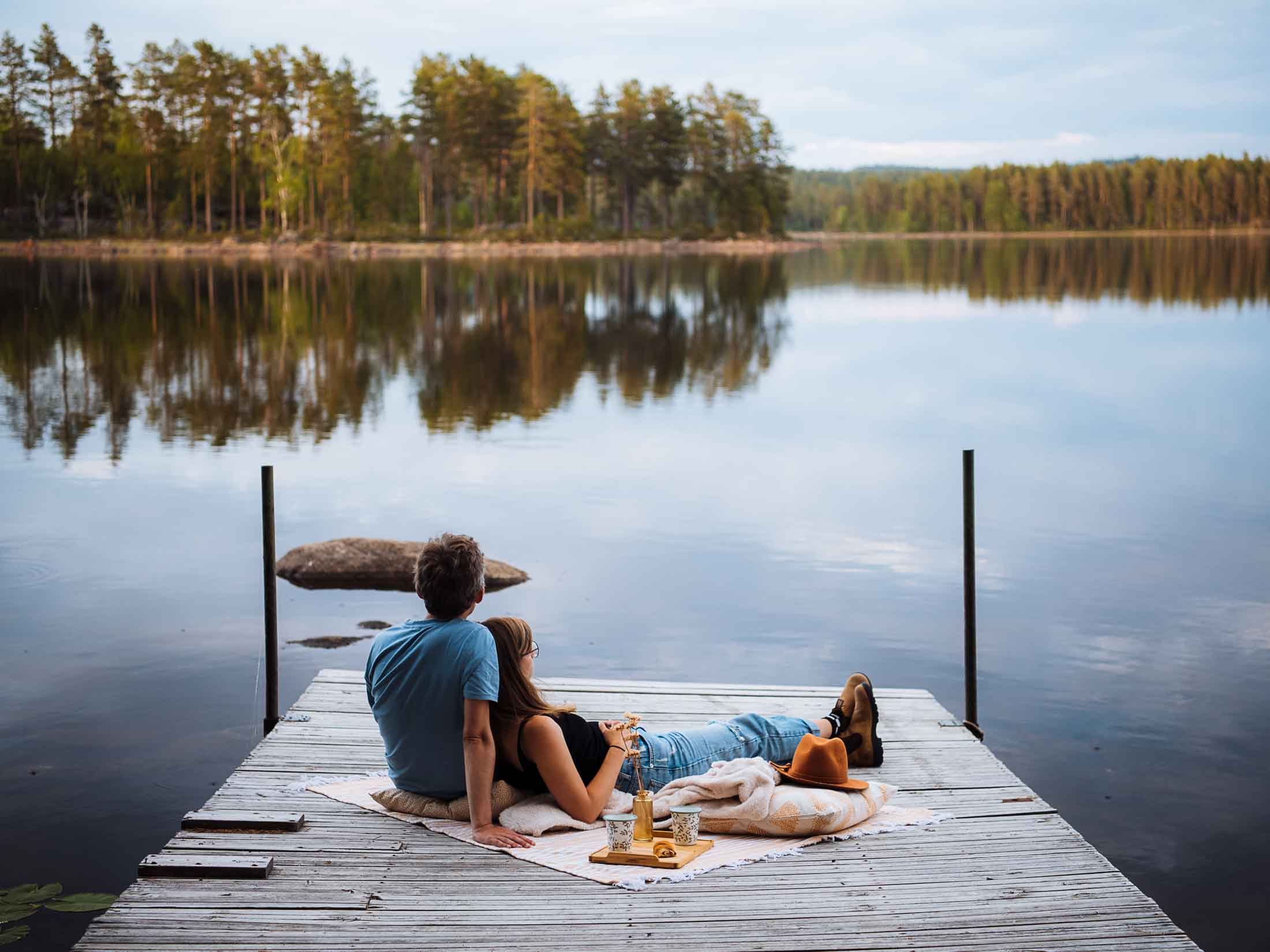 me and florian lying on a picnic blanket on a wooden pier on the lake in sweden