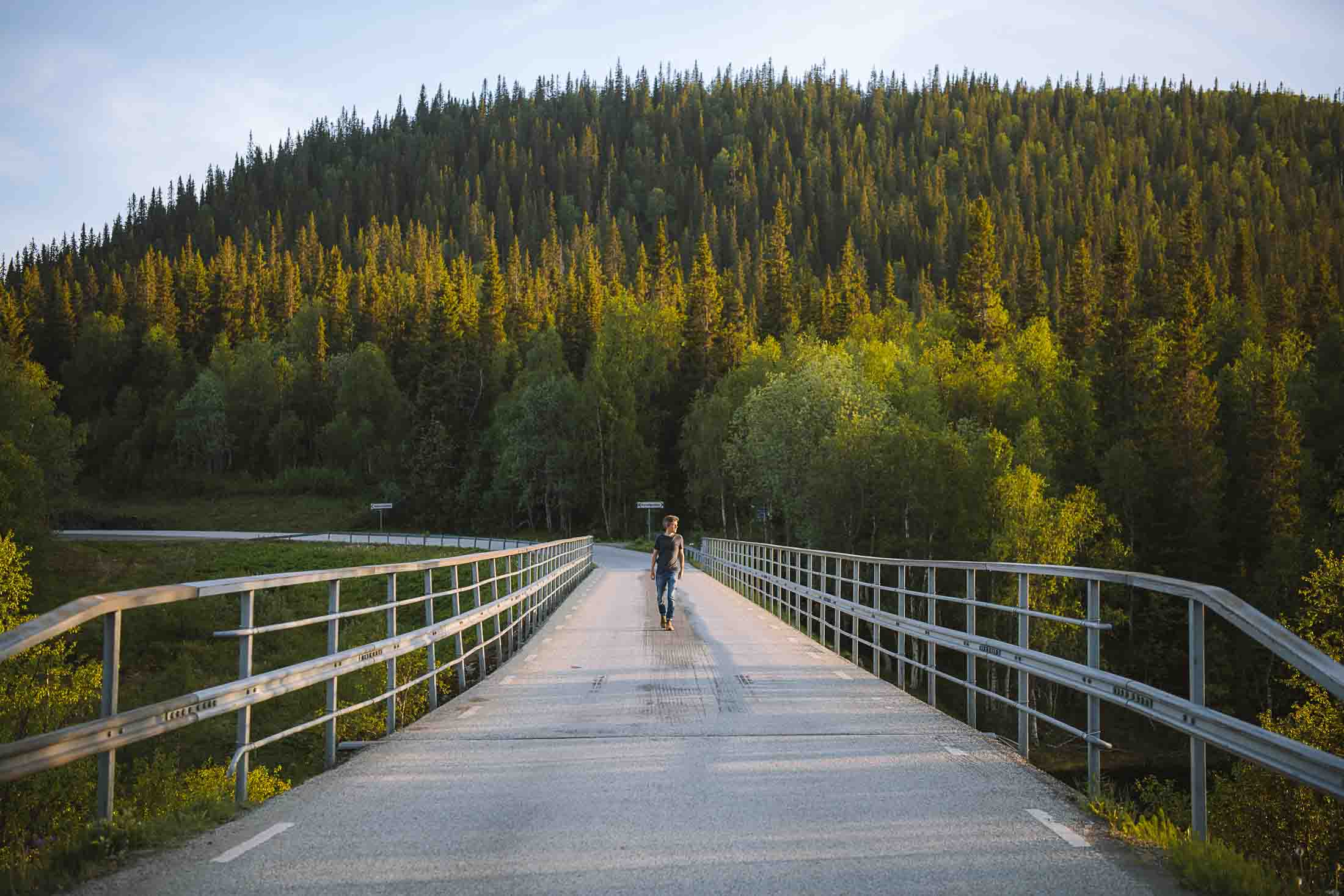 florian walking over a bridge with the forest in the background