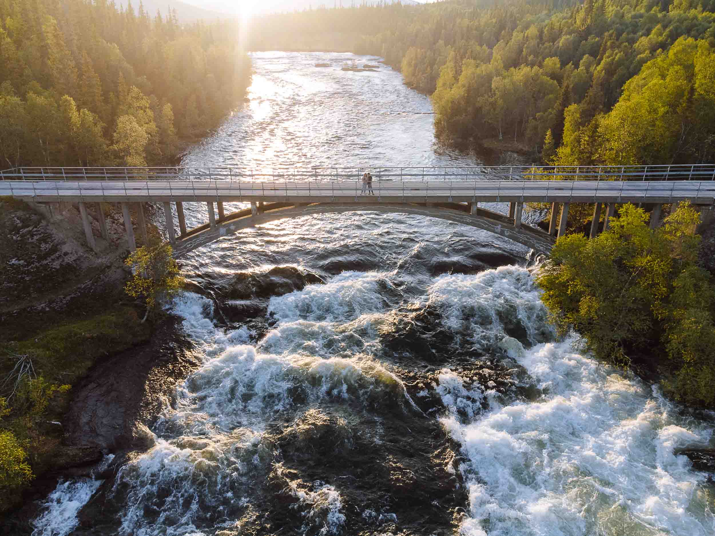 me and florian standing on a bridge over a swirling river in sweden on the vildmarksvägen