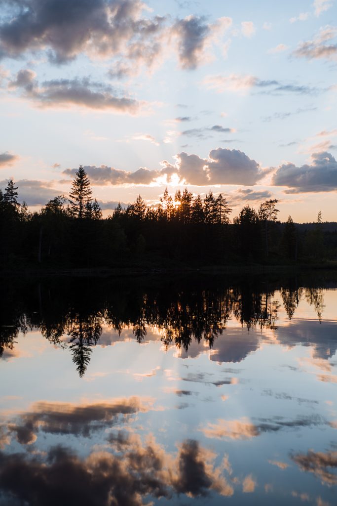 crazy sunset behind the trees with a reflection in the water of the lake